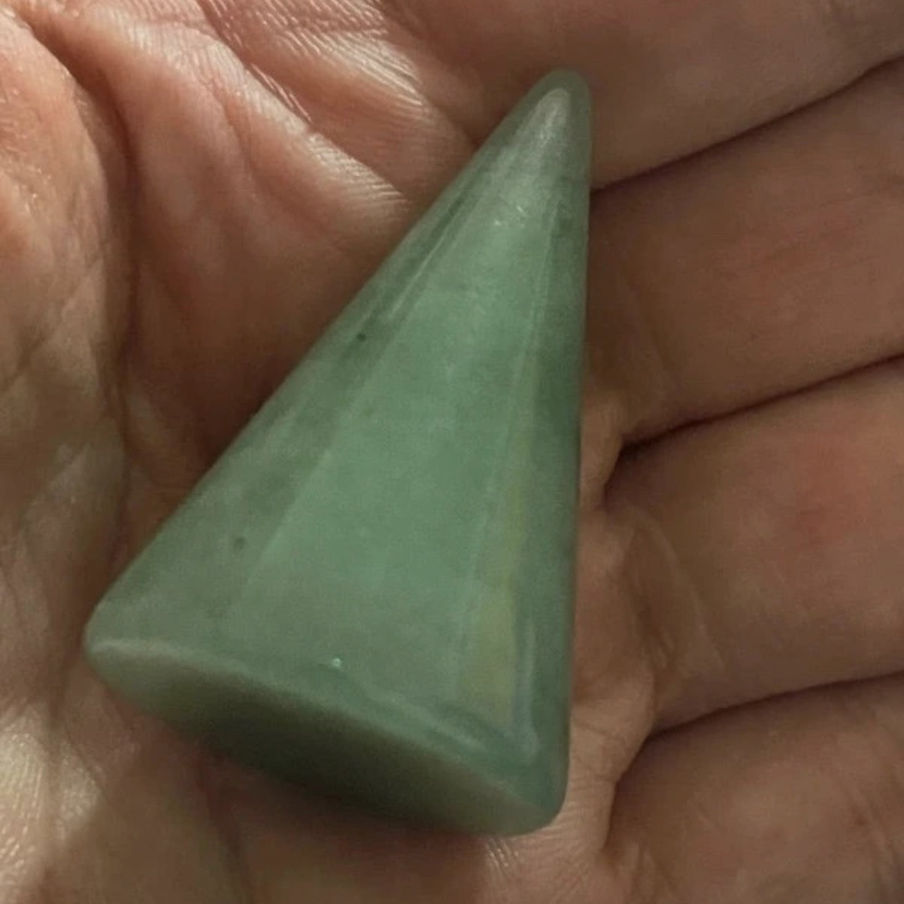 Green triangular stone held in a hand