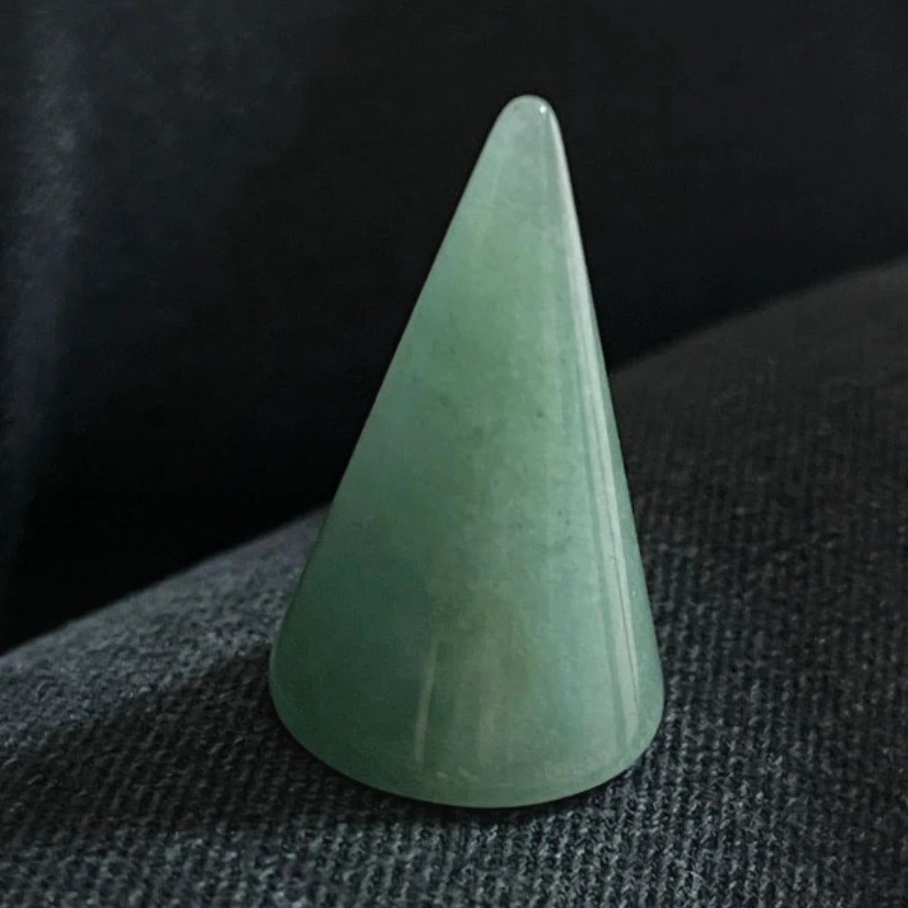 Green stone cone on a textured dark surface