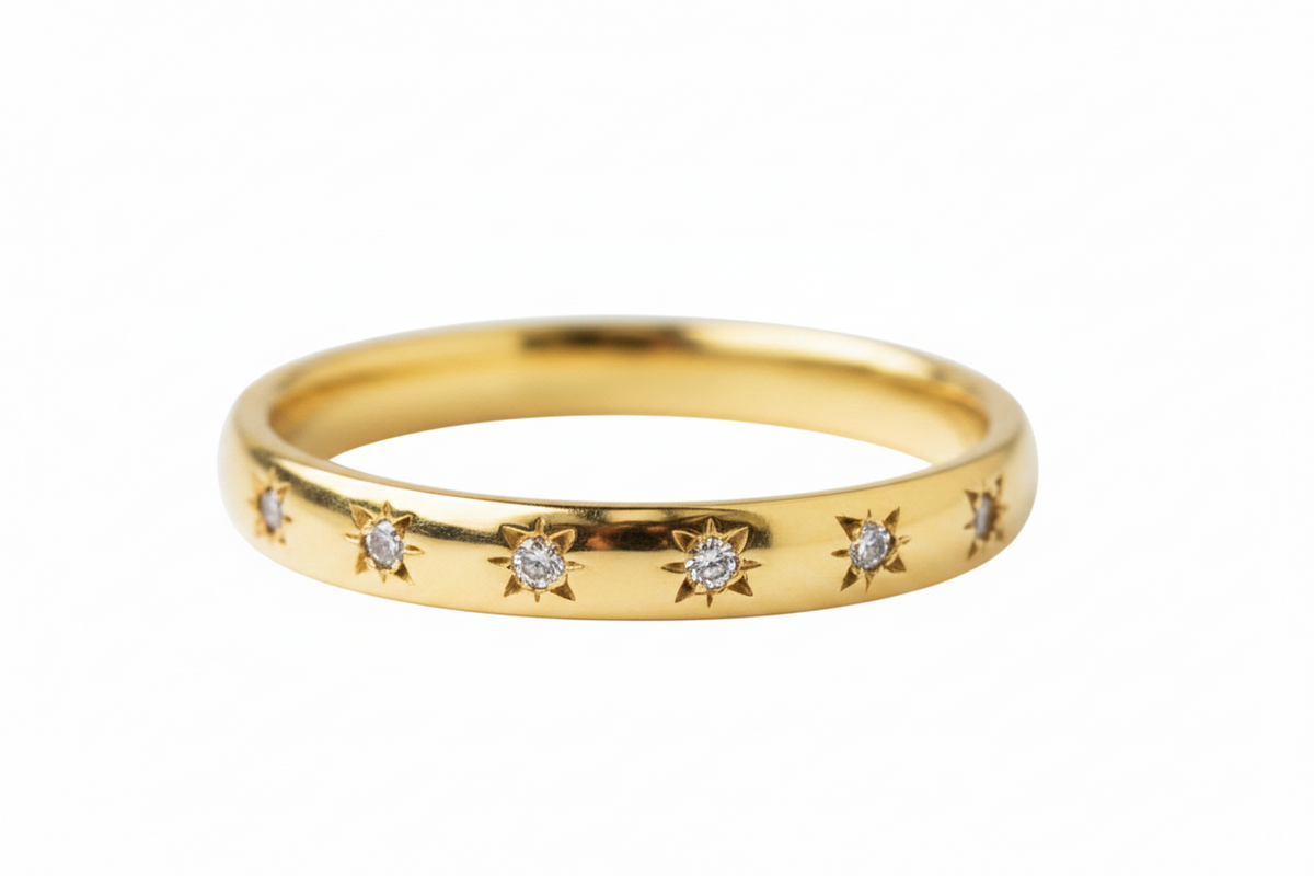 A yellow gold eternity ring featuring a row of small starburst motifs, each inlaid with a round clear gemstone, set against a plain white background.