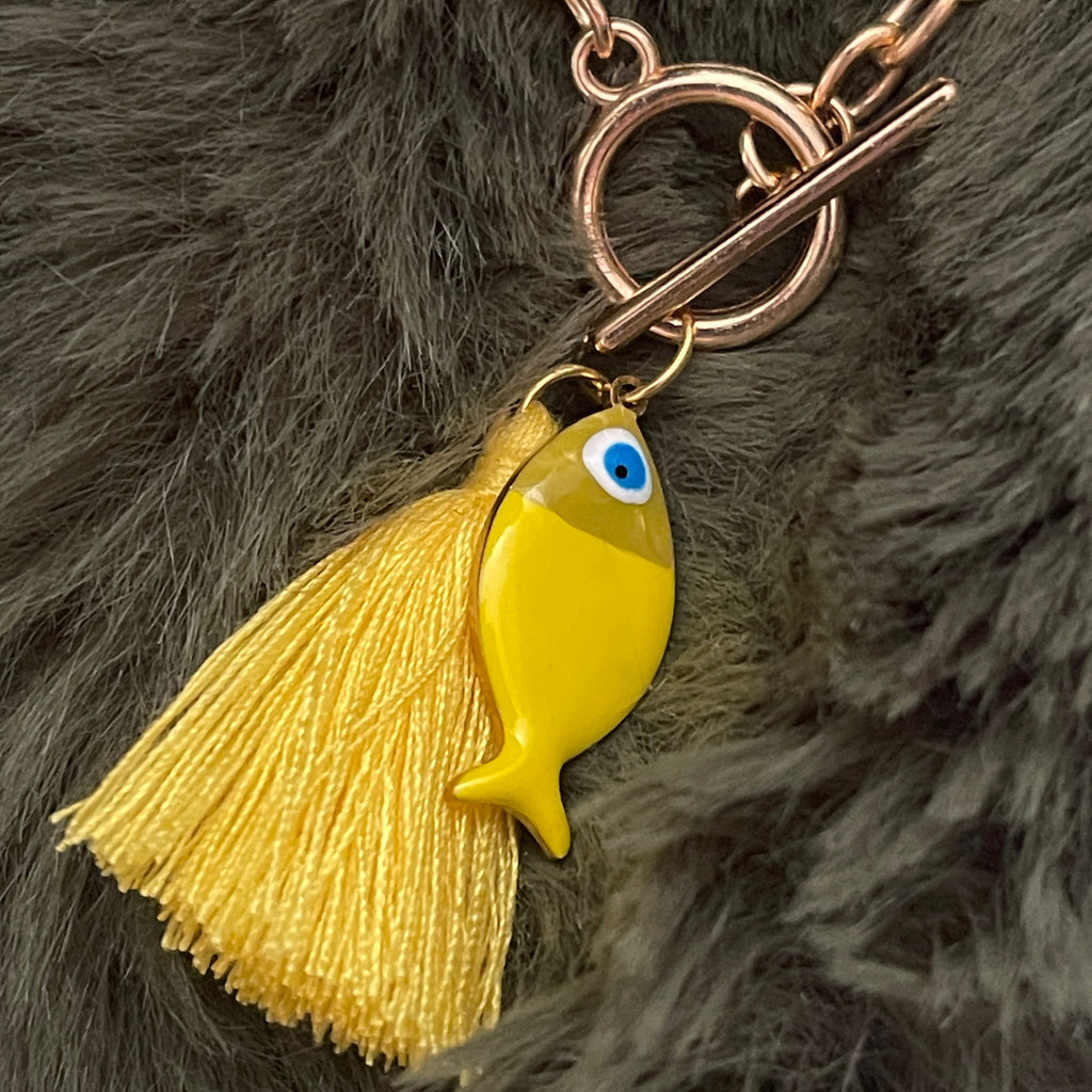 Yellow fish charm with tassel on a keychain against a fur background