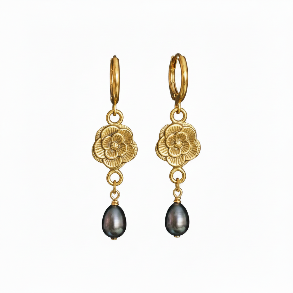 A pair of gold dangle earrings with engraved floral motifs and dark teardrop freshwater pearls, shown on a plain white background.