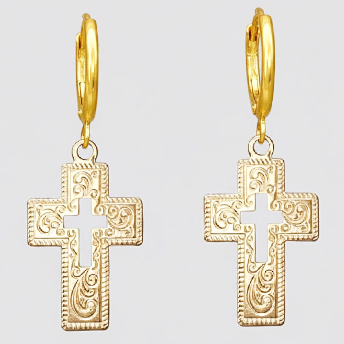 Gold cross earrings on a light grey background.