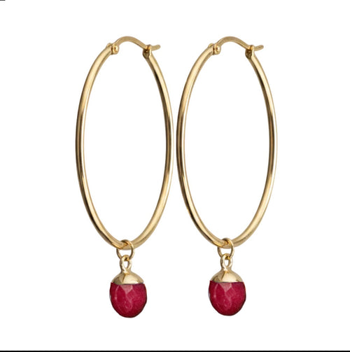 Gold hoop earrings with red gemstones on a white background