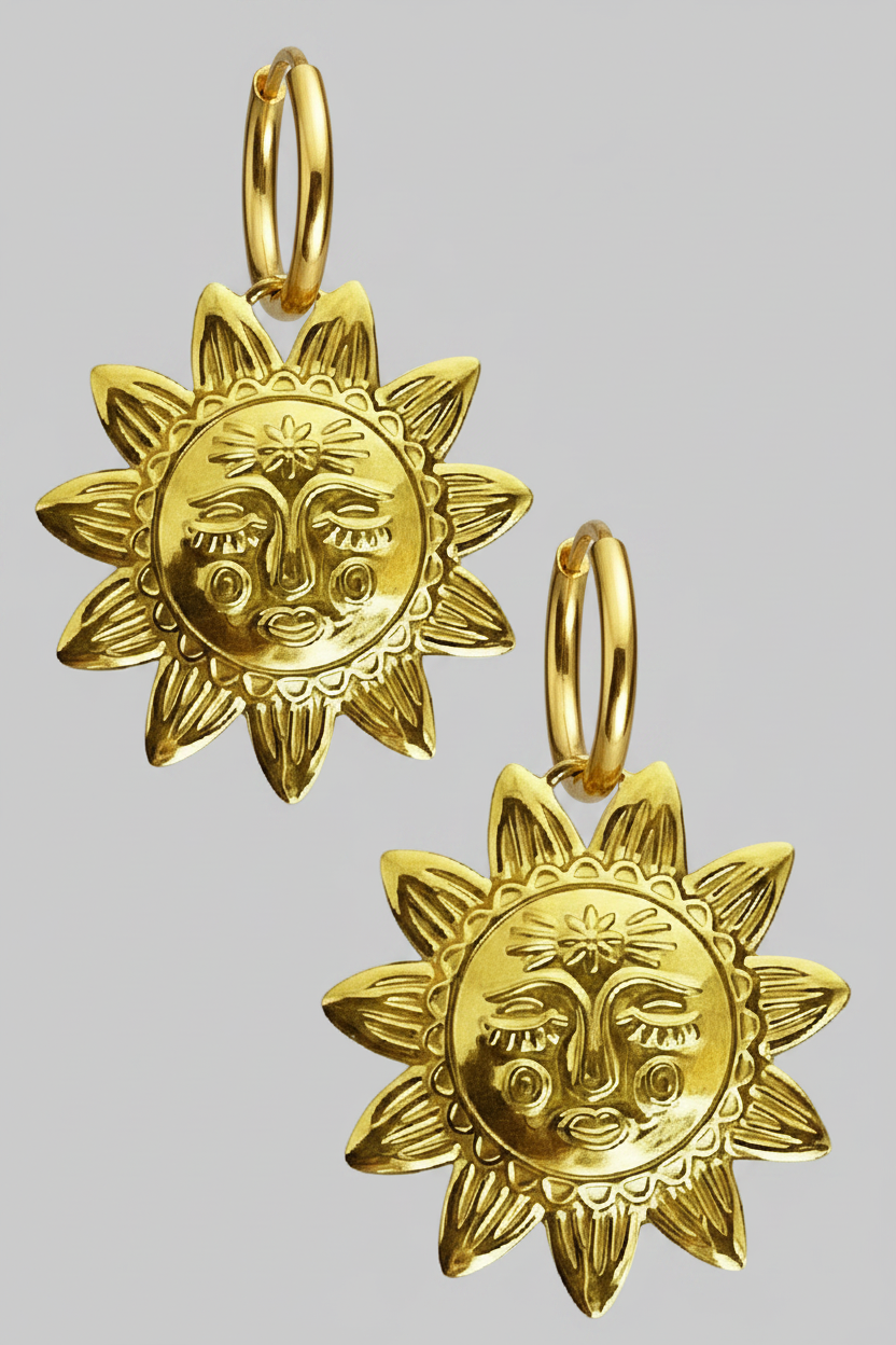 Gold sun-shaped earrings with face design on a grey background