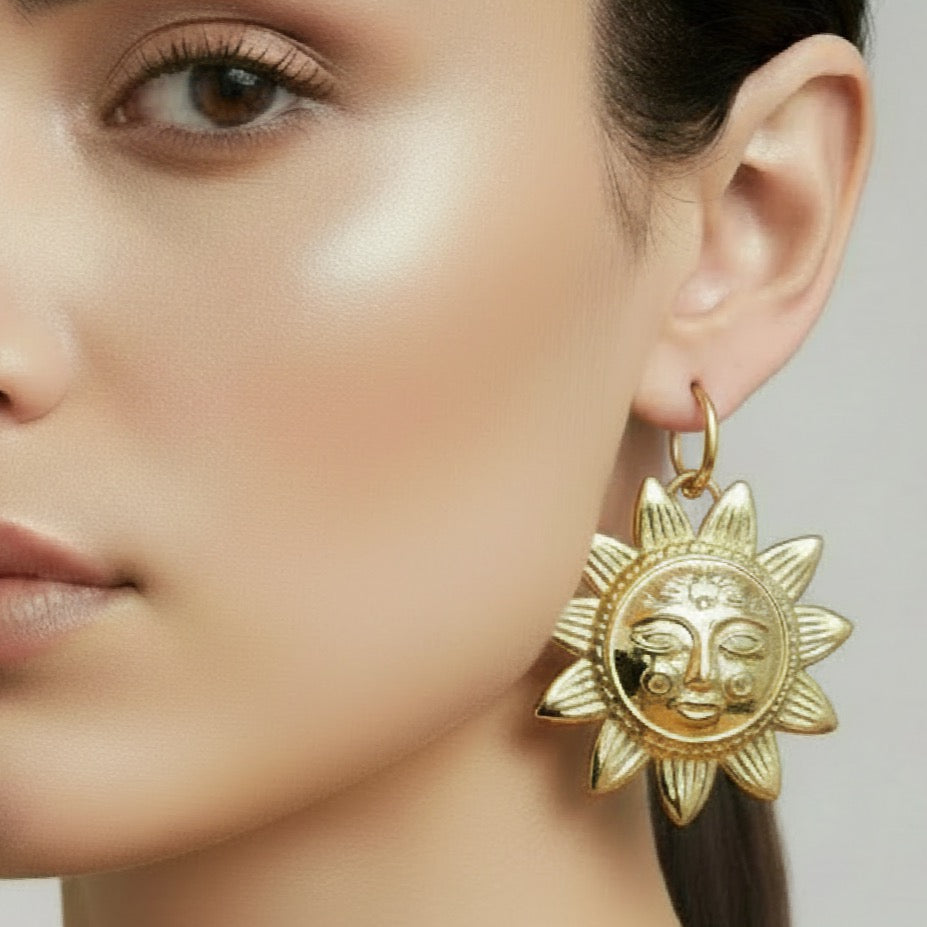 Gold sun-shaped earring worn by a model on a neutral background
