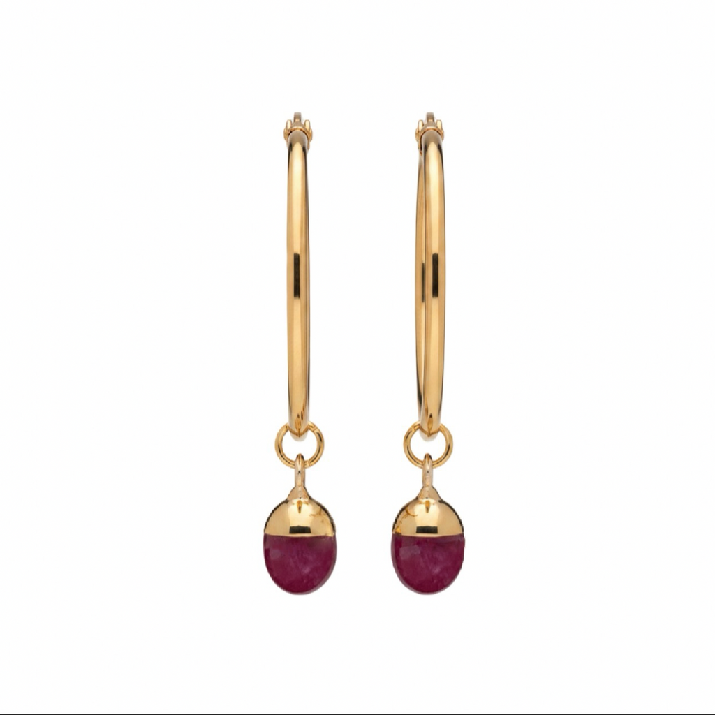 A pair of gold  hoop earrings with a deep pink gemstone, shown against a plain white background.