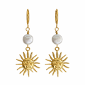 A pair of gold-tone dangle earrings featuring a small round white pearl and a dangling sun face charm, shown against a plain white background.