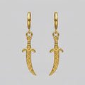 Gold dagger-shaped earrings on a light grey background
