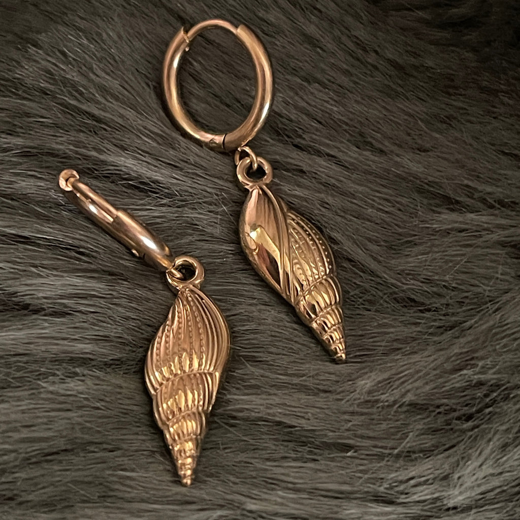 Pair of gold shell earrings on a fur surface