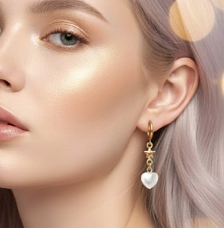 Close-up of a woman wearing a gold earring with a heart-shaped pearl pendant.