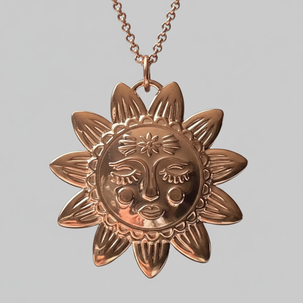 Gold sun-shaped pendant necklace on a light grey  background