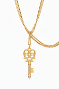 Gold key-shaped pendant on a gold chain against a white background