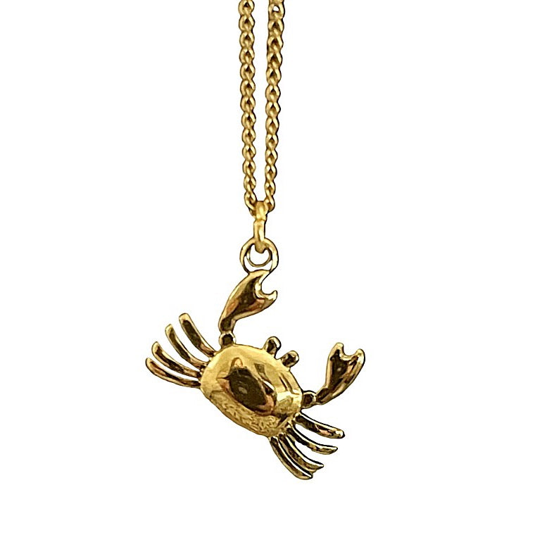 Gold crab pendant on a chain against a white background