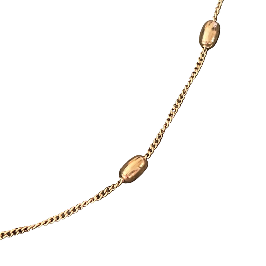 Gold necklace with small gold beads on a white background