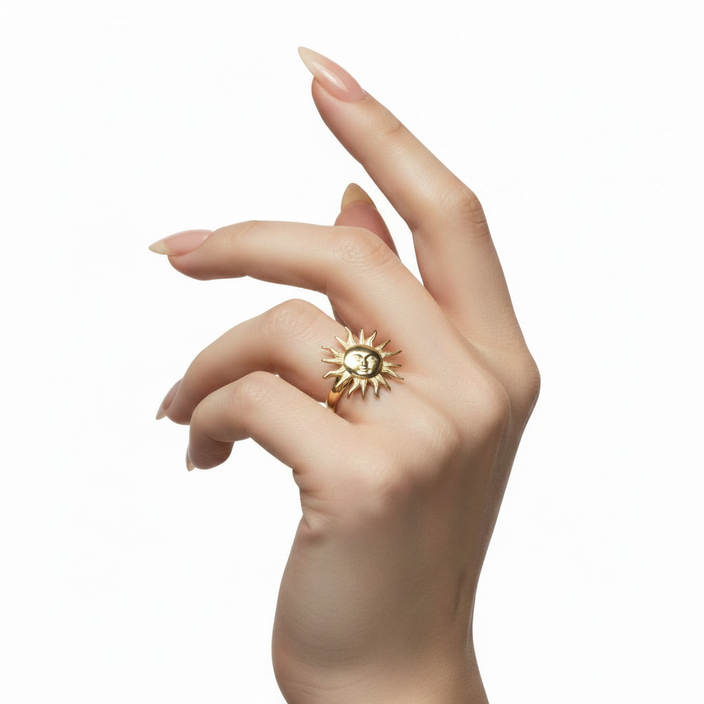 Hand wearing a gold ring with a sun design on a white background