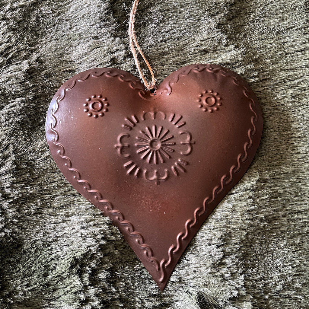 Decorative heart-shaped brown ornament with embossed patterns on a textured surface