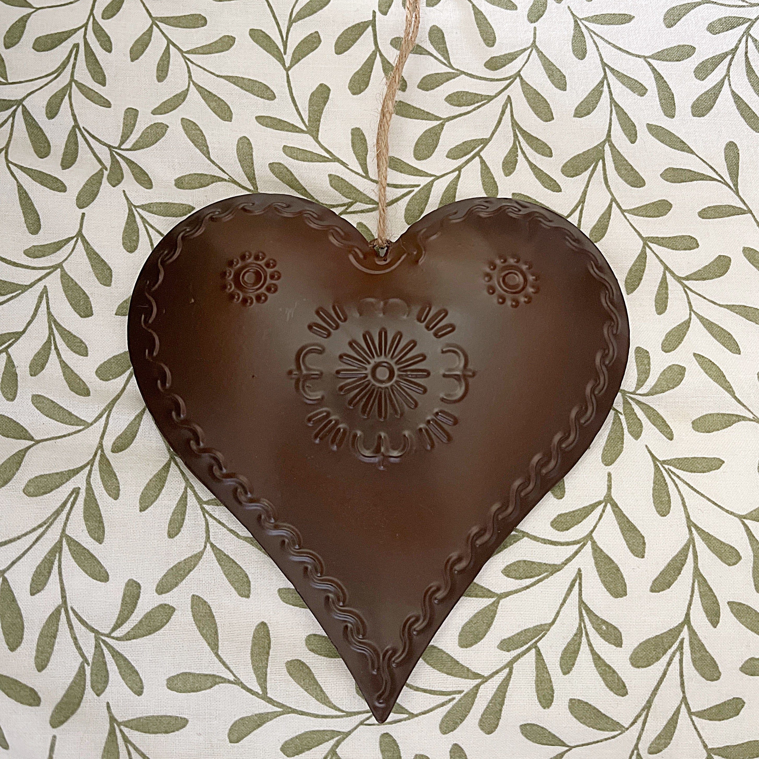 Decorative heart-shaped object with embossed patterns on a leaf-patterned background