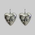 Pair of silver heart-shaped earrings with intricate designs on a light gray background