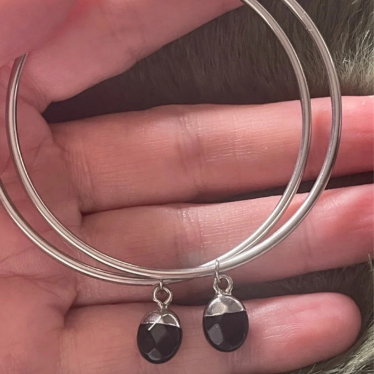 Silver hoops with black crystals held in hand 