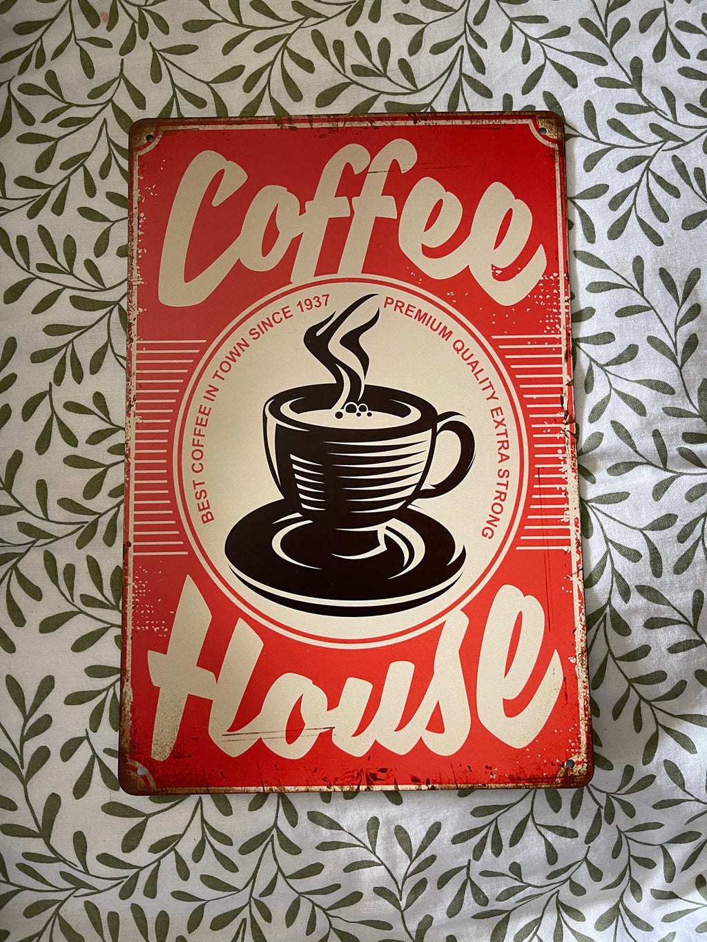 Vintage-style 'Coffee House' sign with a coffee cup graphic on a patterned background