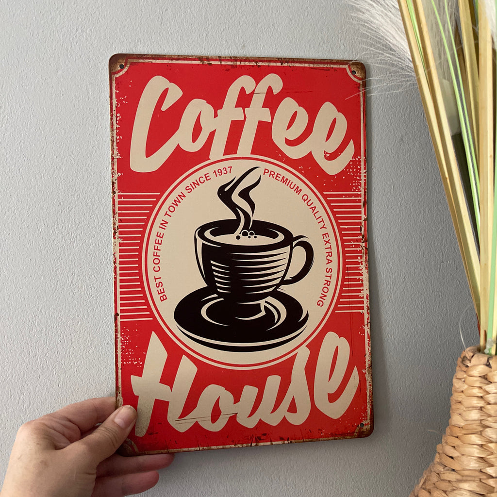 Red and white sign with a coffee cup graphic and 'Coffee House' text on a gray wall.