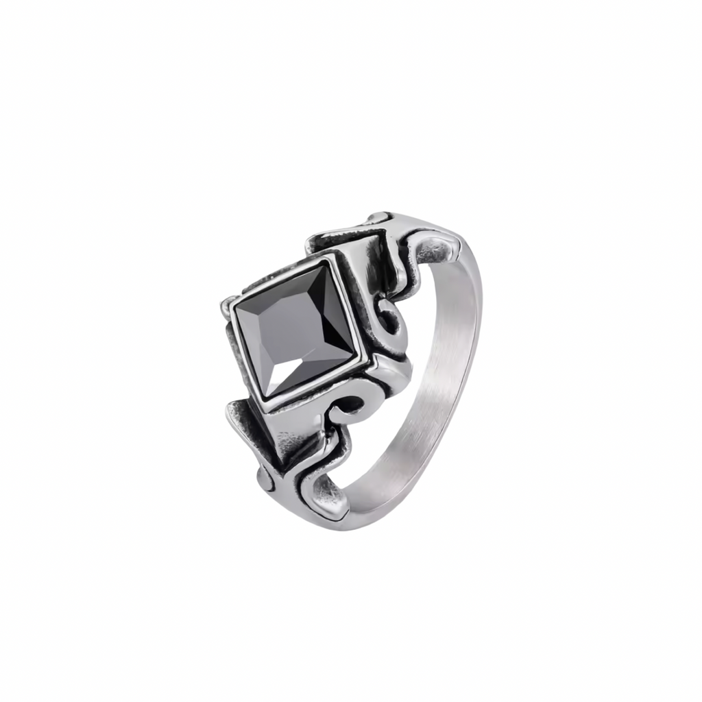 A silver-toned gothic-style ring featuring a large, faceted black diamond-shaped gemstone in the center, set against a clean white background.