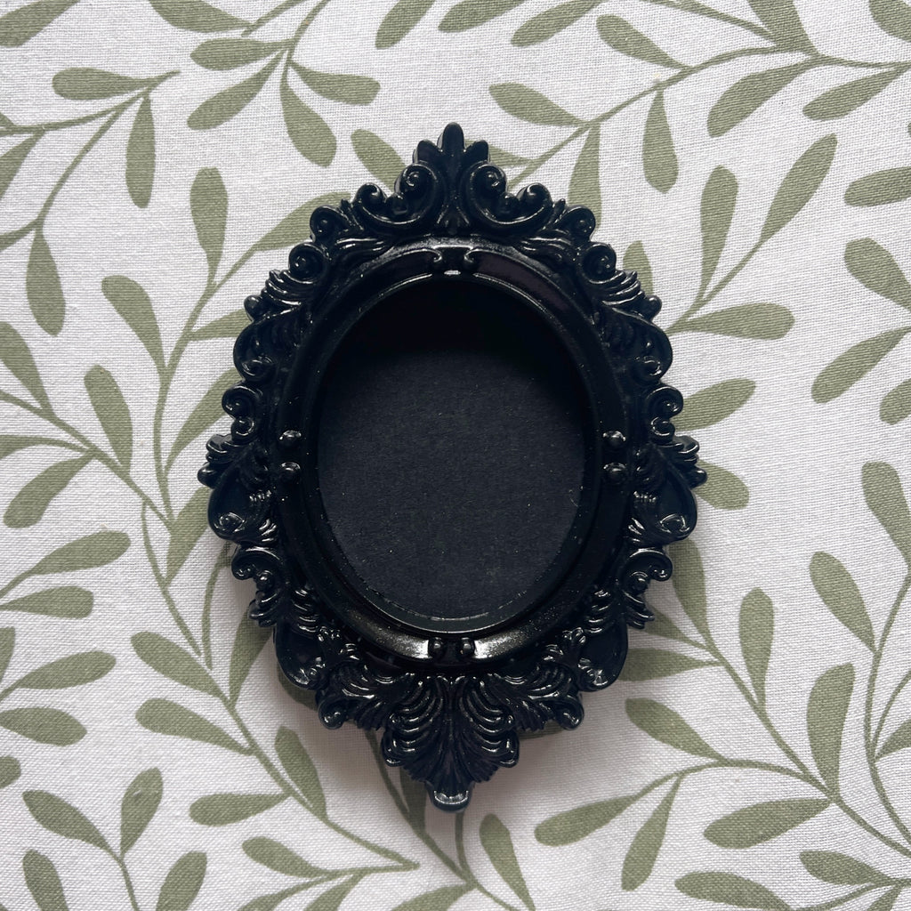 Decorative black frame on a white fabric background with green leaf pattern