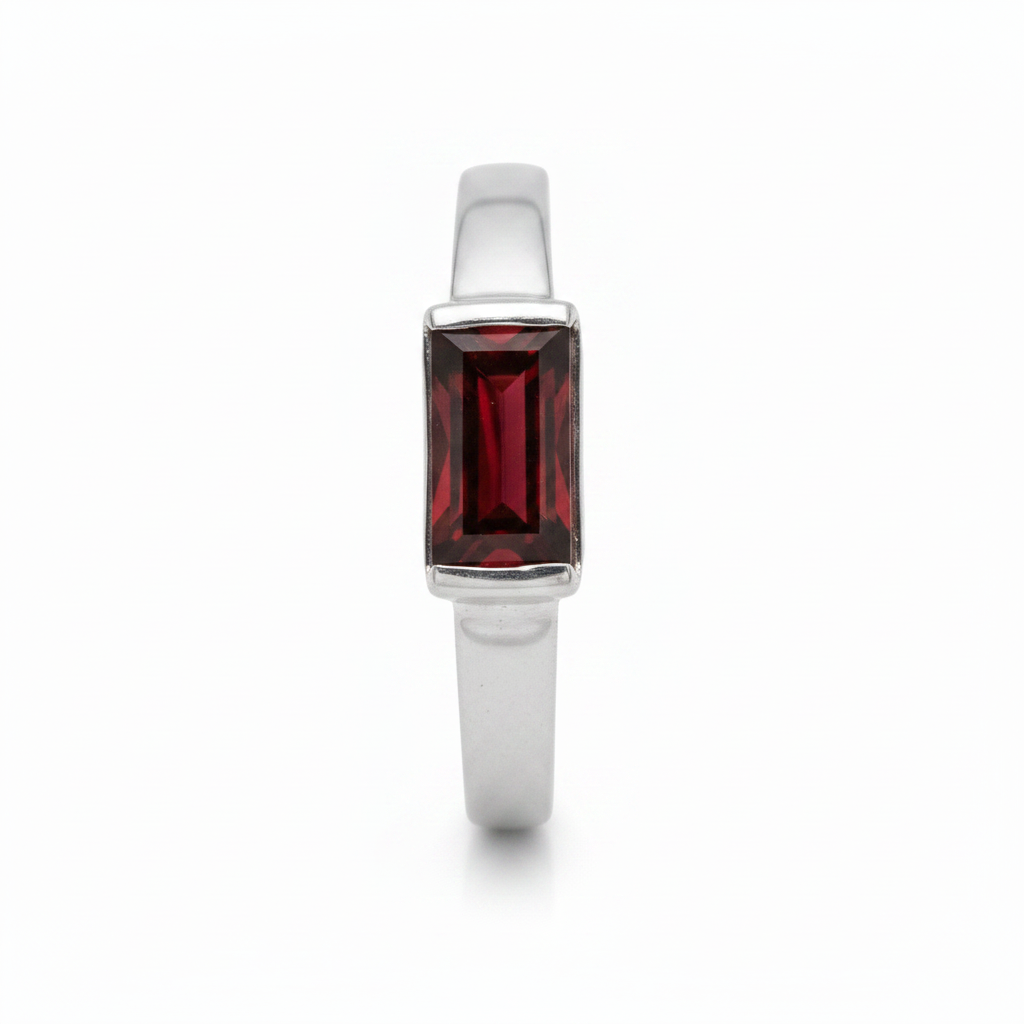A silver ring with a rectangular red gemstone, against a white background.