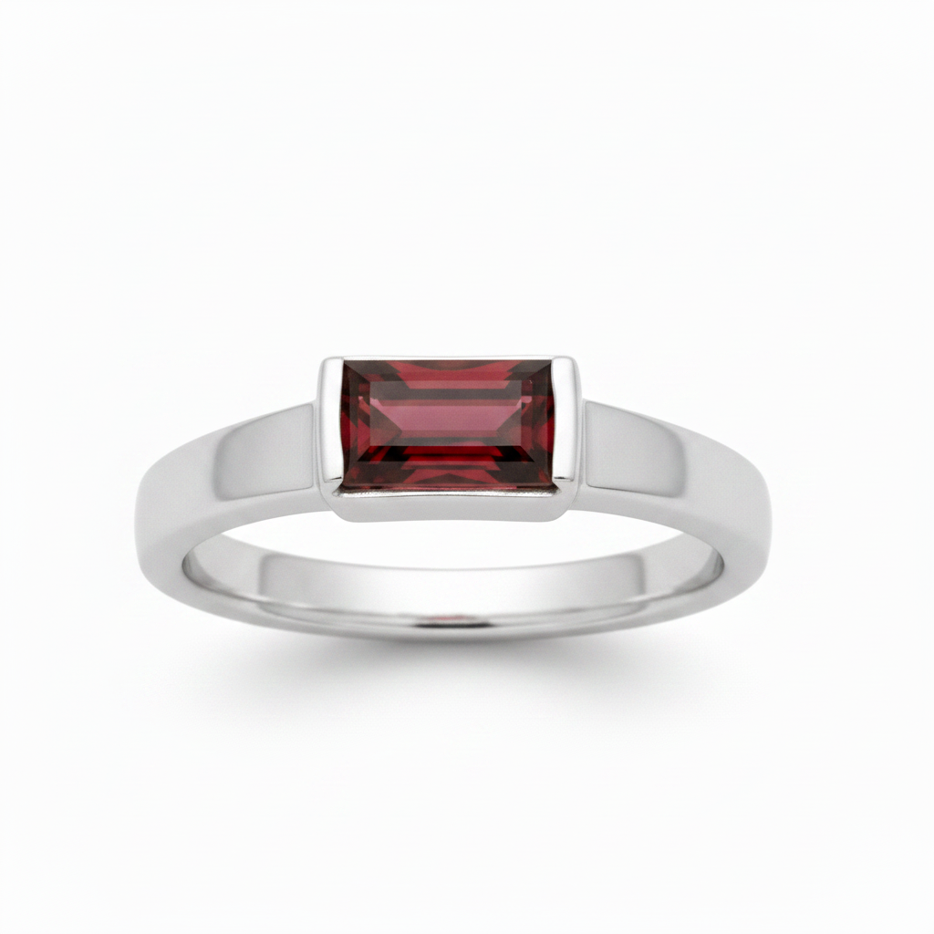 A silver ring featuring a rectangular baguette-cut deep red gemstone, shown on a clean white background.