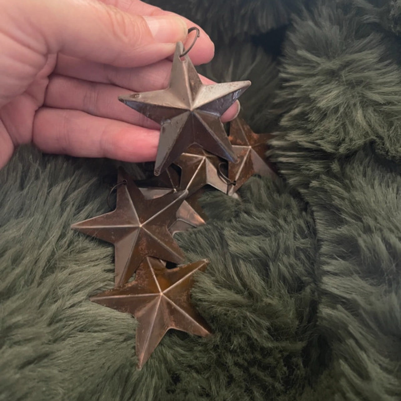 Hand holding a star-shaped ornament against a green textured background