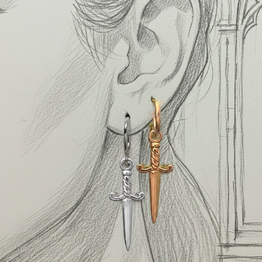 Gold and silver sword-shaped earrings on a pencil-sketch background