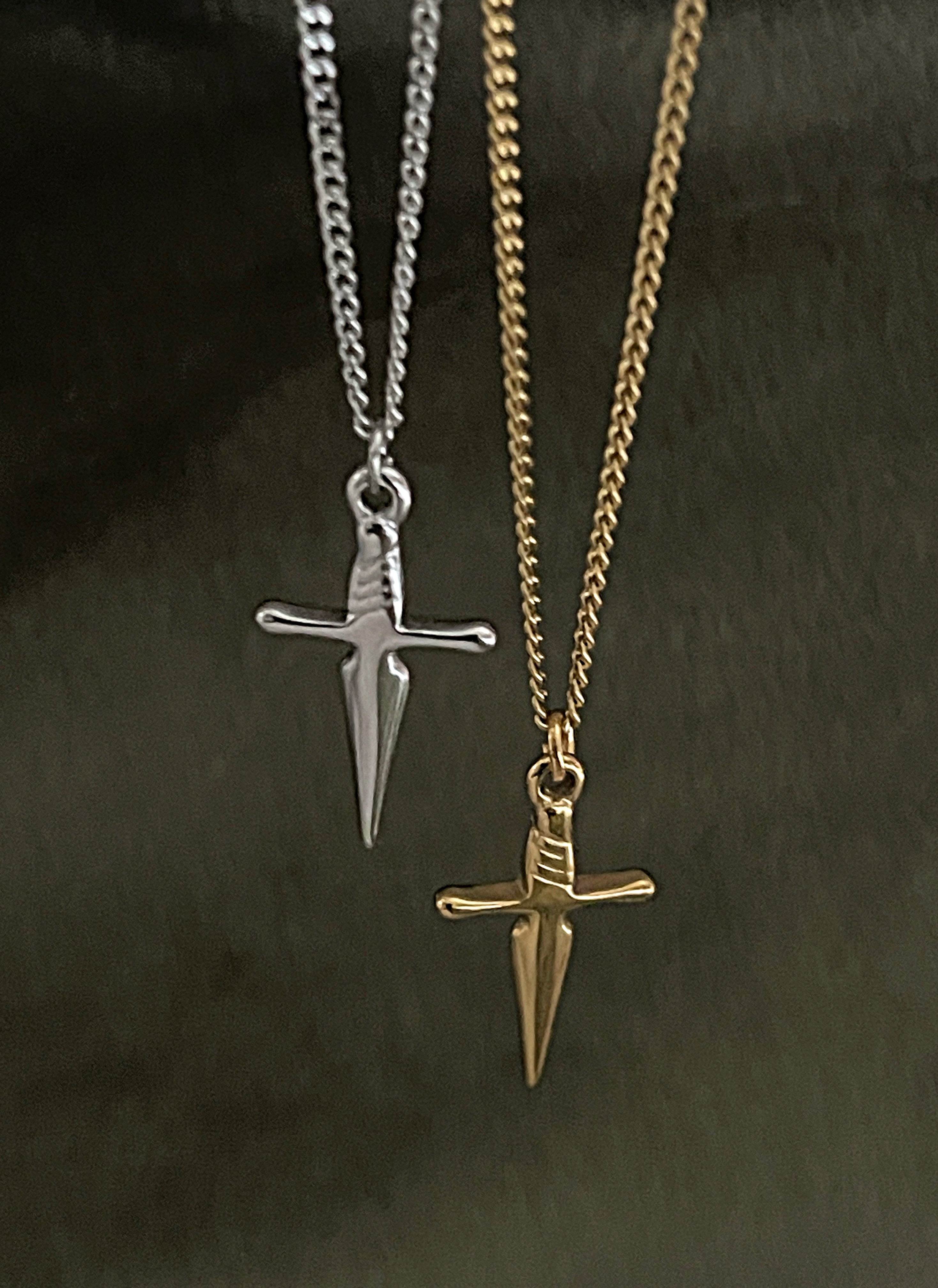 Two necklaces with sword pendants, one silver and one gold, on a dark background.