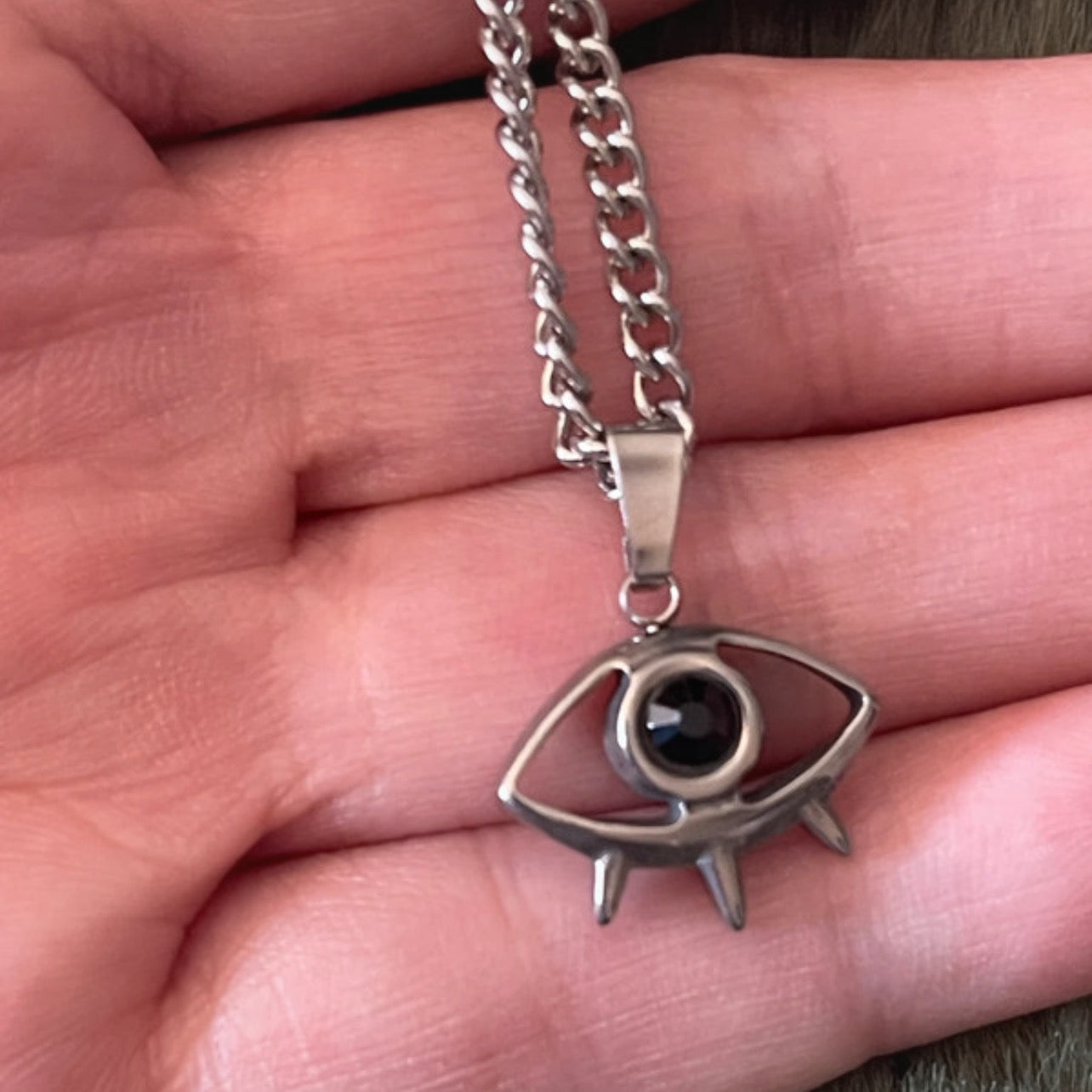 Silver necklace with an eye-shaped pendant on a hand