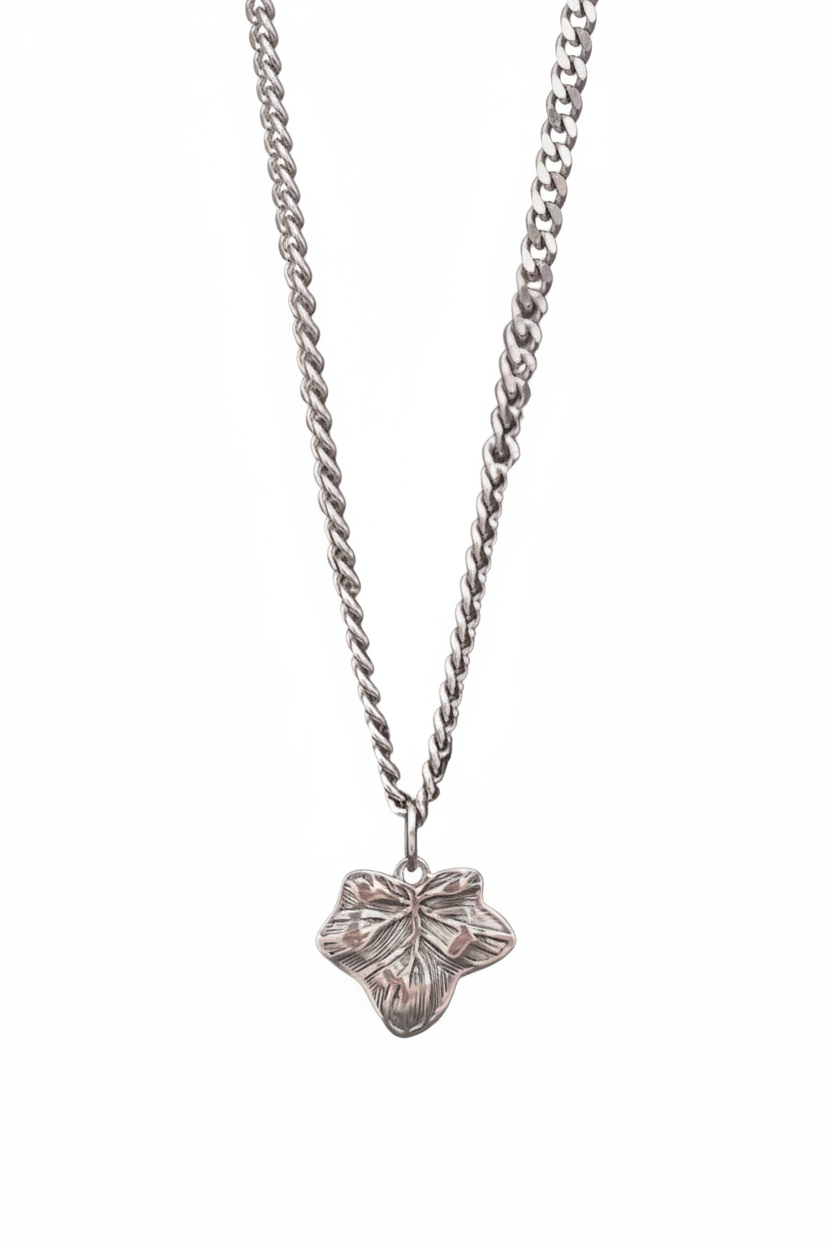 A silver-toned necklace featuring a textured, leaf-shaped pendant suspended from a curb chain, shown against a plain white background.