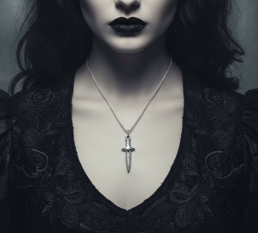 Person wearing a black lace garment with a silver dagger pendant necklace.