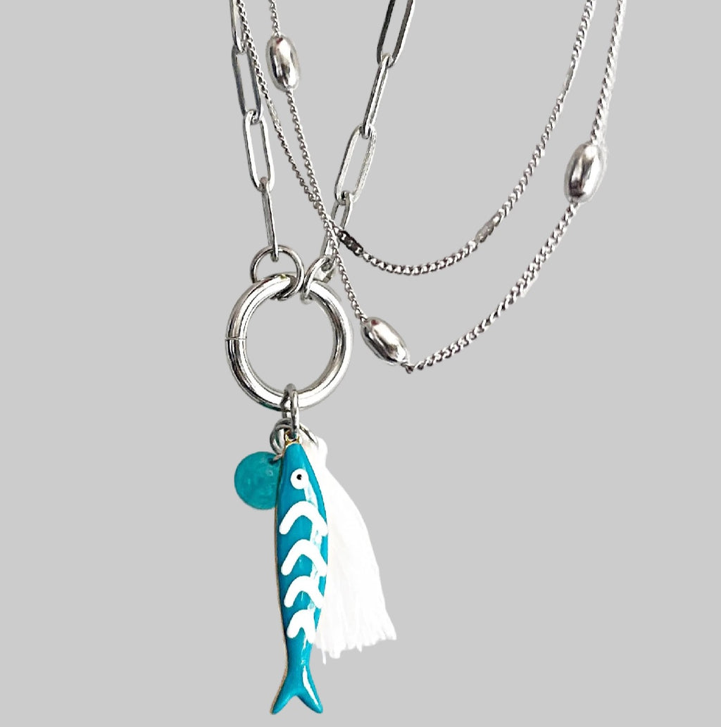 Necklace with a turquoise fish charm on a grey background