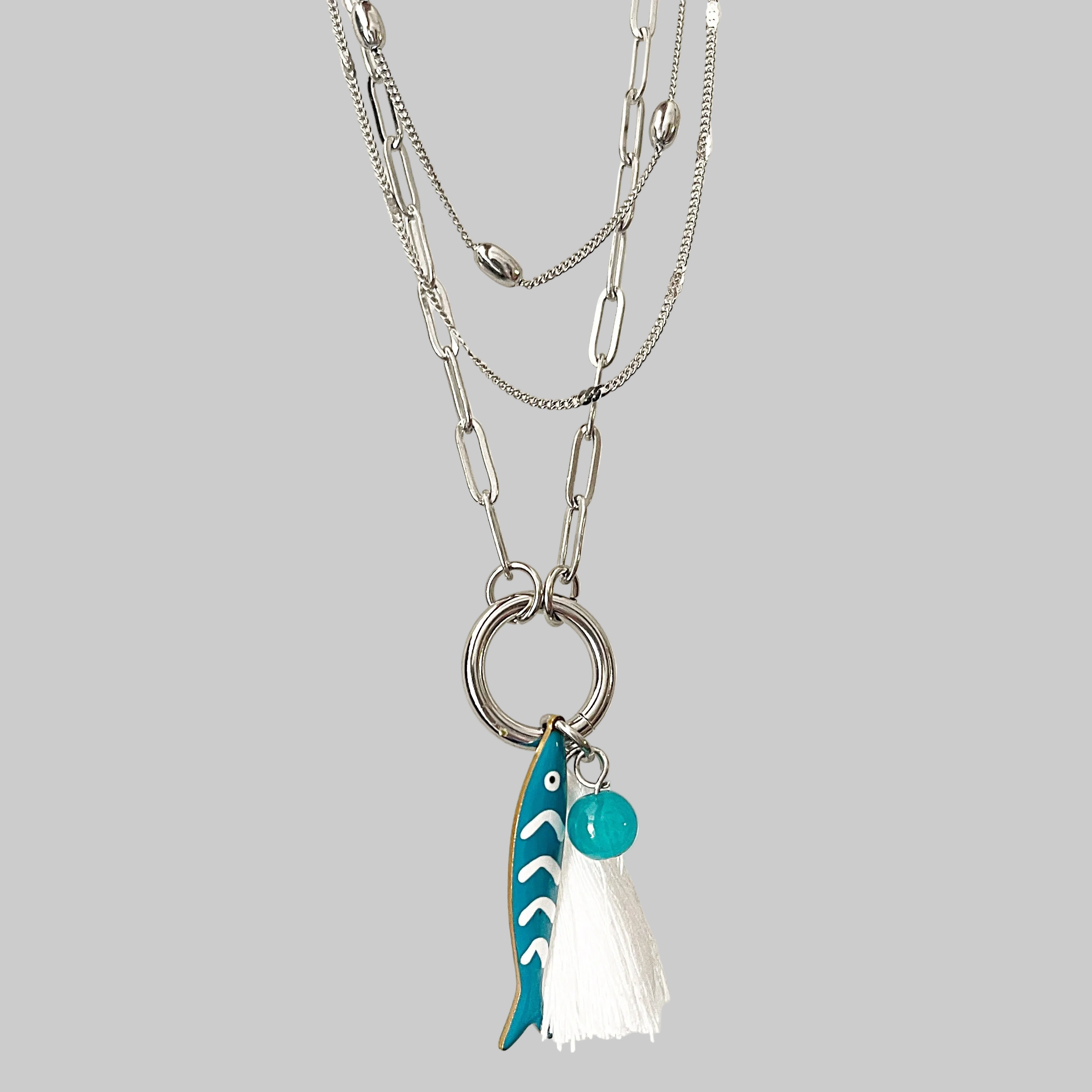 Necklace with a fish-shaped pendant and turquoise bead on a grey background
