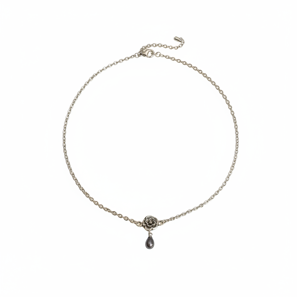 A delicate silver chain necklace featuring a small silver rose charm and a dark teardrop pendant, displayed on a clean white background.