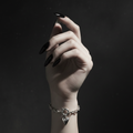 Silver chain bracelet with a heart-shaped charm on a dark background 