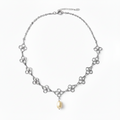 A silver-tone chain necklace featuring a series of small interlocking floral or clover-like motifs with a single dangling pearl at the center, shown on a clean white background.