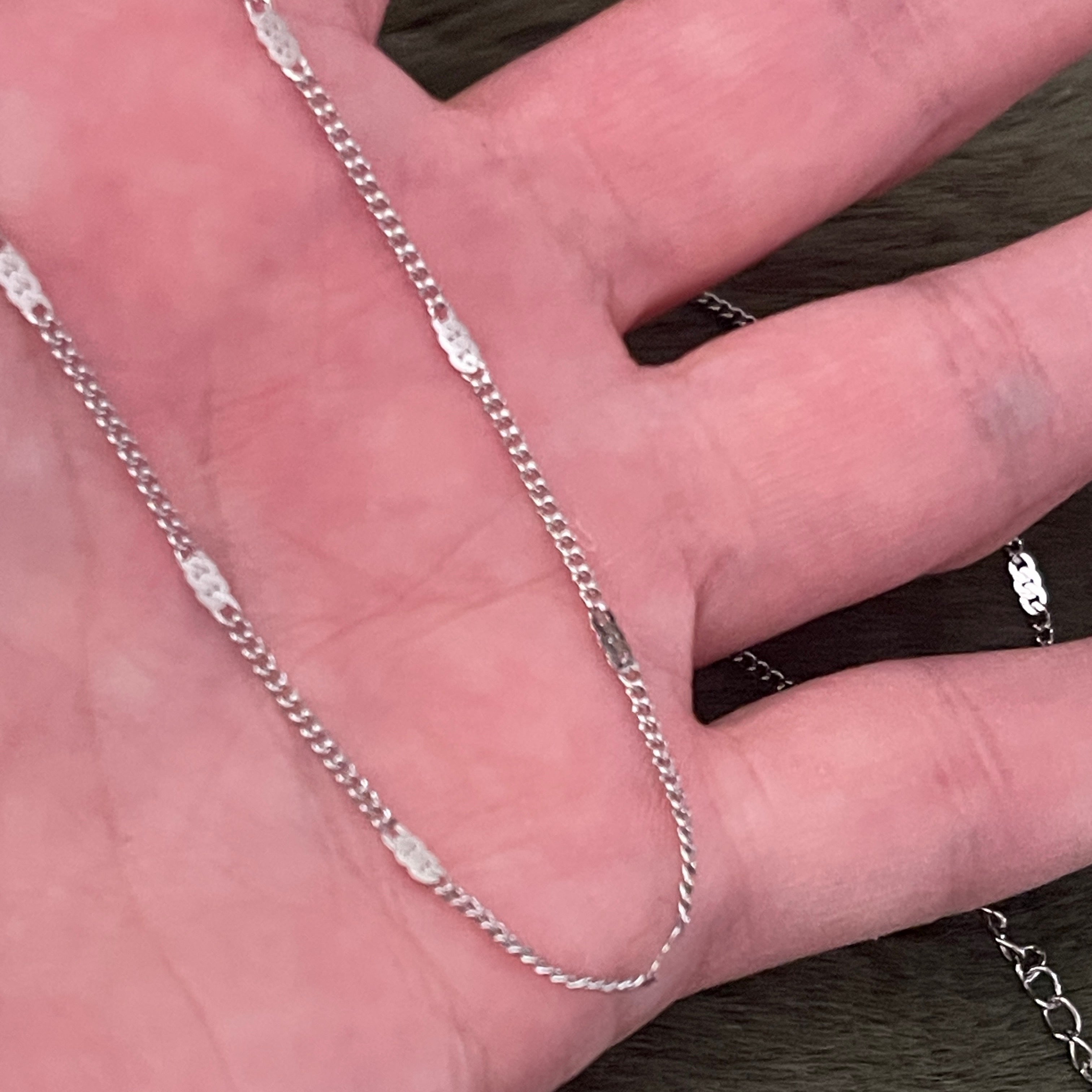 Silver chain necklace draped over a hand