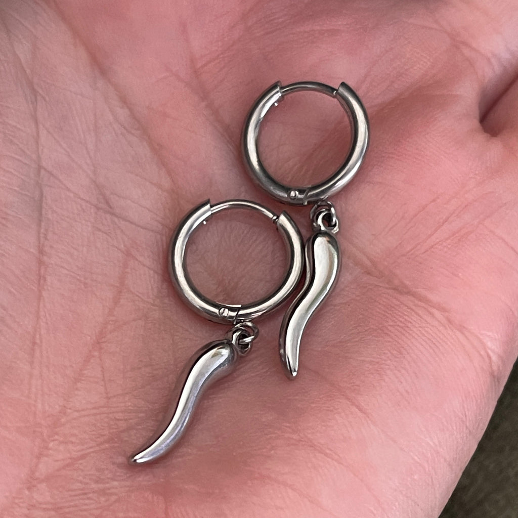 Silver hoop earrings with unique designs held in a hand.