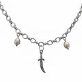 A silver-tone chain necklace featuring a central curved dagger pendant, flanked by two small, irregular white pearl beads on either side of the chain, shown against a plain white background.