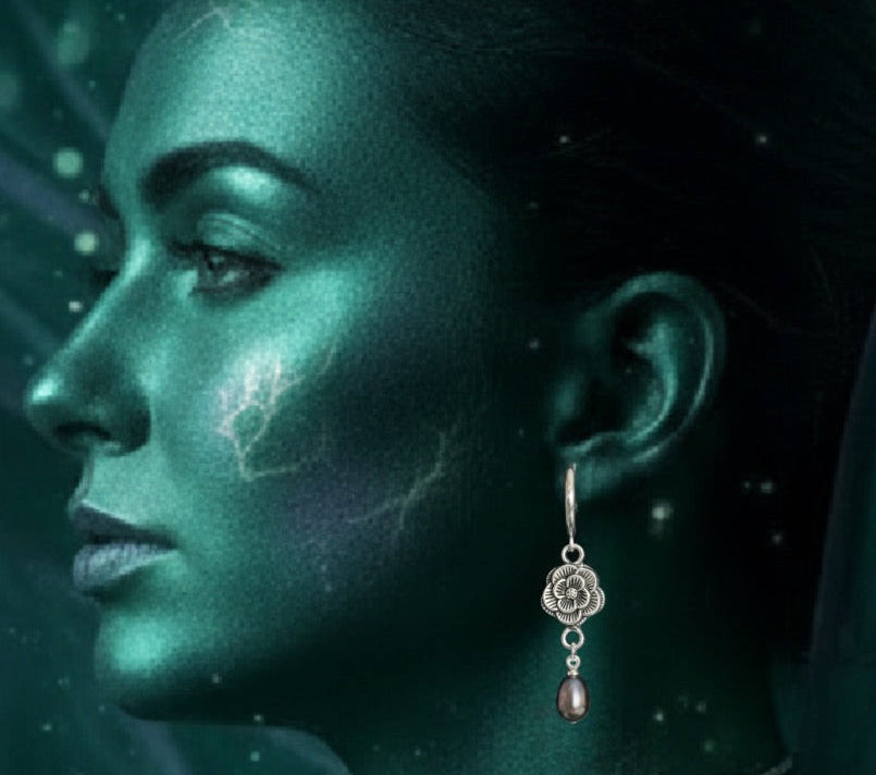 A woman in profile wearing a dangling earring against a dark, starry teal background.