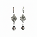A pair of silver-toned drop earrings featuring an engraved floral pendant and a dangling teardrop-shaped dark pearl, shown against a plain white background.