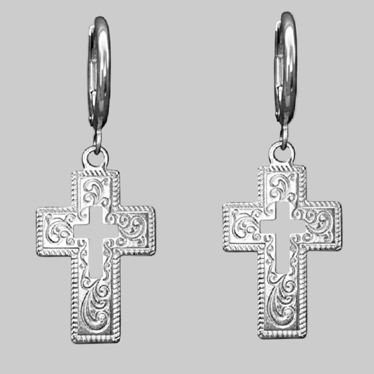 Silver cross earrngs on a light grey background.