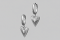 Silver heart-shaped earrings on a gray background