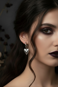 Close-up of a woman wearing a silver heart-shaped earring with a dark background