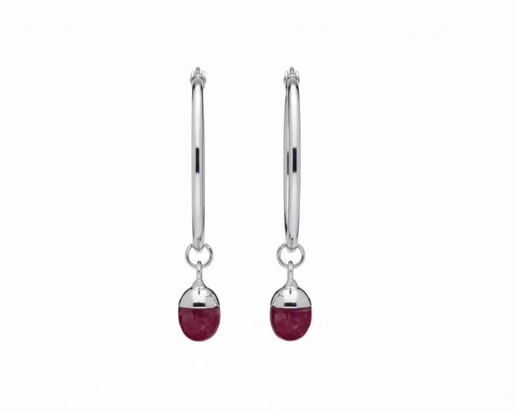 Pair of silver hoops with a pink oval-shaped crystal on a white background