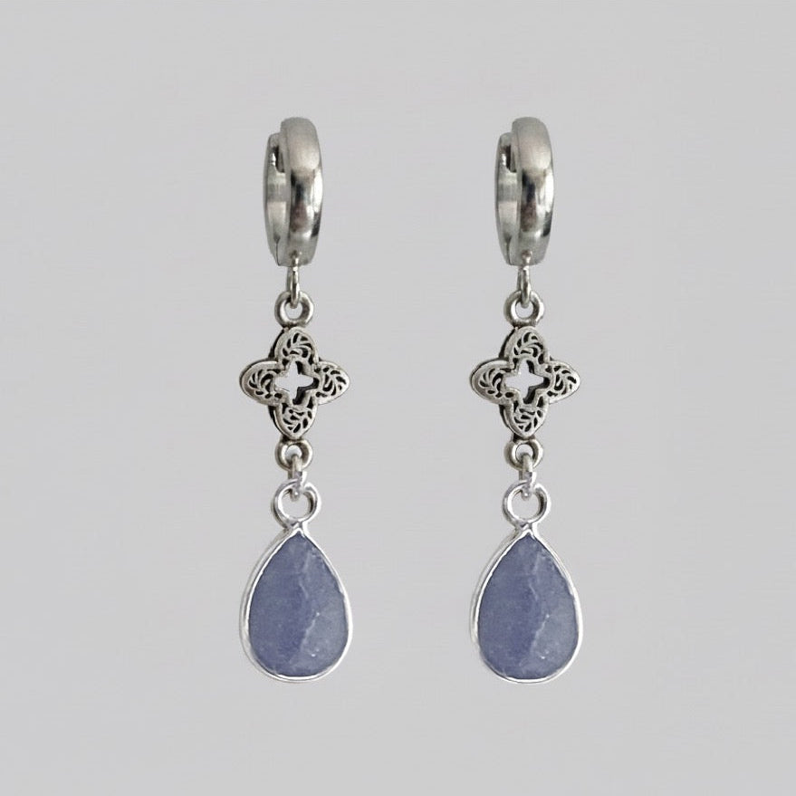 Pair of silver earrings with teardrop-shaped stones on a gray background